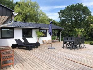 a wooden deck with chairs and a table and umbrella at SJ314-Haderslev-Kelstrup-Norreskov-42 in Kelstrup Strand