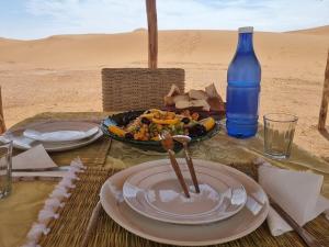 a table with plates of food and a bottle of water at Epic Erg Chigaga Desert Camp in El Gouera