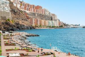 a view of a beach with buildings and the water at Boutique apartment with BBQ terrace and ocean views in Tabaiba