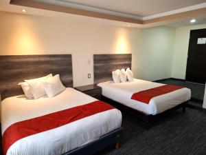 um quarto de hotel com duas camas com lençóis vermelhos e brancos em Hotel ALO! Express em Torreón