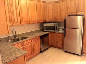 a kitchen with wooden cabinets and a stainless steel refrigerator at Mayflower Hospitality Hostel in Washington, D.C.