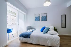 ein weißes Schlafzimmer mit einem Bett mit blauen Kissen in der Unterkunft Beach Apartment by Portugal Portfolio in Paço de Arcos