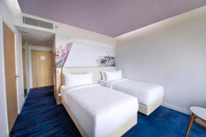 a room with two beds and a table and chairs at OZO Medini Malaysia in Nusajaya