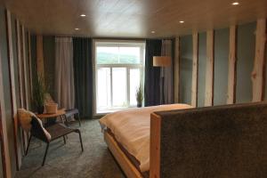 a bedroom with a bed and a chair and a window at Åsjord Farmhouse in Oldra