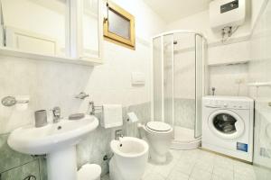 a white bathroom with a sink and a washing machine at Patresi Mare - Goelba in Mortigliano