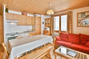 un salon avec un canapé rouge et une cuisine dans l'établissement Refuge Le Bardeau B1, au Grand-Bornand 8 autres photos