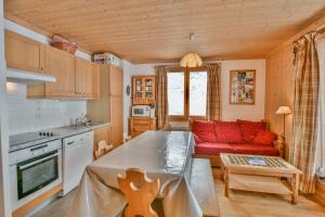 Il comprend une cuisine et un salon avec un canapé rouge. dans l'établissement Refuge Le Bardeau B1, au Grand-Bornand