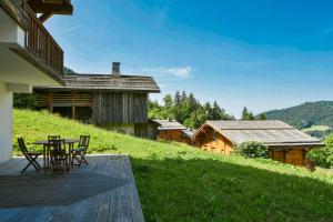 une terrasse en bois avec une table et des chaises sur une colline dans l'établissement Refuge Le Bardeau B1, au Grand-Bornand