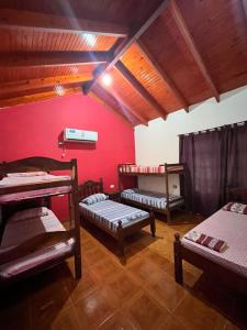 a room with three bunk beds and a red wall at Complejo turístico Anto in Puerto Rico