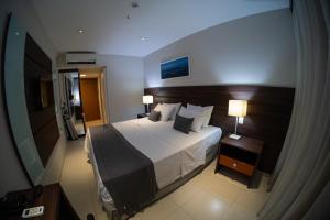 a bedroom with a large bed and two lamps at Hellix Flat Itaboraí in Itaboraí