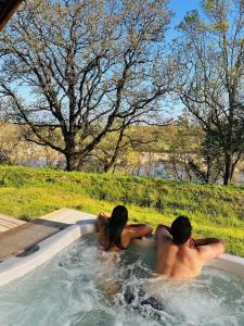 un homme et une femme assis dans un bain à remous dans l'établissement DAMONA LODGES, à Vairé