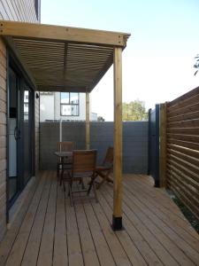 une terrasse en bois avec auvent, table et chaises dans l'établissement Les Amarres, maison bois avec terrasse proche mer, à La Rochelle