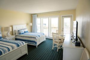 a hotel room with two beds and a desk and a window at Surf & Sand Beach Motel in South Yarmouth +36 photos