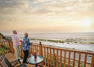 an older couple standing on a deck looking at the ocean at Poppy Lodge LE 17 Ocean's Edge Park in Morecambe
