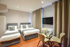 a hotel room with two beds and a table and chairs at Imperial Court Studios in London