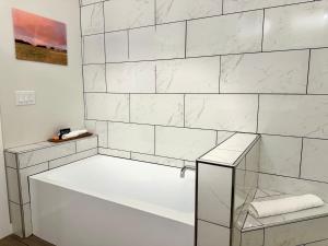 a white tiled bathroom with a tub and a shower at The Benjamin Hotel in Watkins Glen