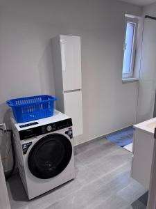 a washing machine with a blue basket on top of it at Appart Wavre, 2ch, terrasse, piscine, charme & confort in Wavre +9 photos