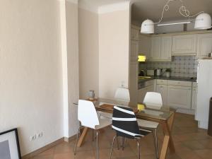 a kitchen with a dining table and white chairs at Immeuble le St Honorat in Cannes