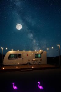 a white rv parked under the night sky with the moon at Flamingo Caravan in Ash Shāb
