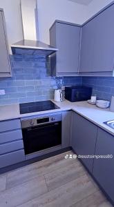 AmleyにあるDress to impress homeの黒いオーブンと青いタイルのキッチン