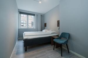 a bedroom with a bed and a chair and a window at MAYA Apartments - Sentrum in Oslo