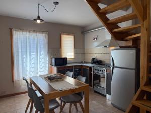 eine Küche mit einem Tisch und einem weißen Kühlschrank in der Unterkunft Paimun 2 - Andarlibre in San Martín de los Andes