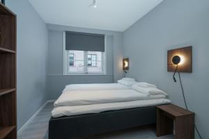 a bedroom with a bed with white sheets and a window at MAYA Apartments - Sentrum in Oslo
