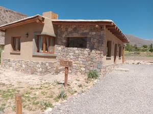 un edificio de piedra con un cartel delante en Cabañas La Nochera, en Tilcara
