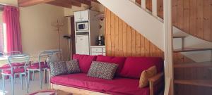 a living room with a red couch and a staircase at Lou cridadé in Laruns +5 photos