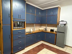 Una cocina con gabinetes azules y un refrigerador. en Summer Suite, en Hermanus