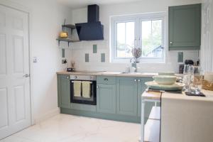 a kitchen with green cabinets and a sink at Sizewell C - Contractor Accommodation in Leiston +5 photos