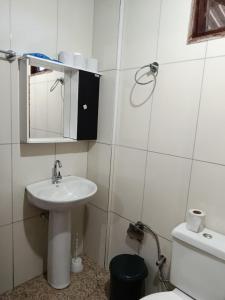 a bathroom with a sink and a mirror and a toilet at Pousada Nosso Cantinho in Guarapari