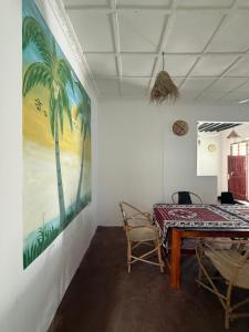 a room with a table and chairs and a painting at Zanzi coconut house in Jambiani