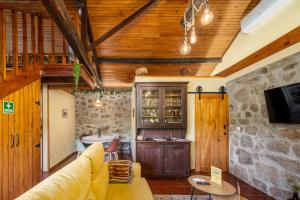 ein Wohnzimmer mit Holzdecken und einer Steinwand in der Unterkunft Quintinha do Varoso - Little Red Cottage House in São Pedro do Sul