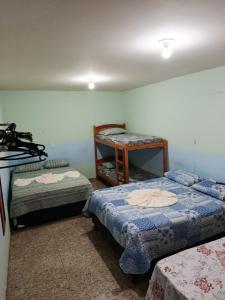a room with two beds and a table in it at Pousada Nosso Cantinho in Guarapari