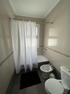 a white bathroom with a toilet and a shower at Hermoso PH en Necochea playa in Necochea