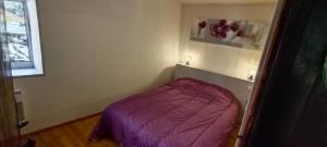 a small bedroom with a purple bed in the corner at Bouerzy in Laruns