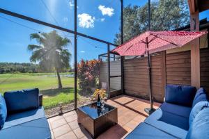 a patio with two blue couches and an umbrella at Tee Time Tranquility in Zephyrhills