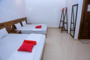 ミリッサにあるOcean Light Mirissaの赤い枕が付いたベッド2台が備わる客室です。