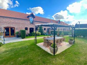 a table and chairs under a gazebo in a yard at Ferme de Montecouvez in Crèvecoeur-sur-lʼEscaut