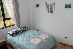 a bedroom with a blue bed with towels on it at Valle Sagrado Mágico in Urubamba