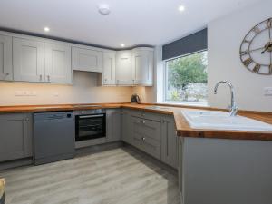 a kitchen with white cabinets and a clock on the wall at Caledfryn in Benllech
