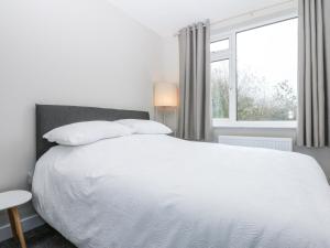 a bedroom with a white bed and a window at Caledfryn in Benllech