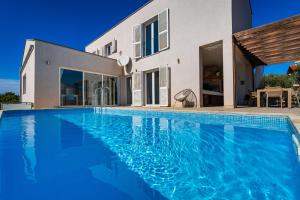 a villa with a swimming pool in front of a house at MY DALMATIA - Sea view villa Anpero with private heated pool and sauna in Maslenica +68 photos