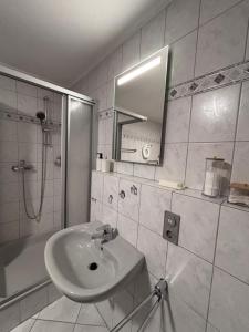 a white bathroom with a sink and a shower at Familienfreundliche Ferienwohnung an der Antoniuslinde im Kurort in Erwitte +17 photos