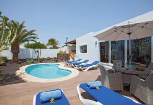 een zwembad met stoelen en een tafel en een parasol bij Villa Esencia in Puerto del Carmen