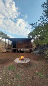 een vuurplaats in een veld met een gebouw bij Glocke Mountain Camp, Cabin in Outjo
