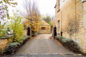 a cobblestone driveway leading to a house with a gate at Delabere House - Luxury Cotswolds Holiday Apartments in Moreton in Marsh