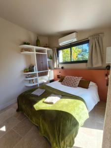 Un dormitorio con una cama grande con una manta verde. en La Grange d'Andrea, en Saint-Étienne-de-Fontbellon