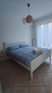 een slaapkamer met een bed met een blauw dekbed en twee ramen bij Appartamento Polpenazze - Relax in collina con piscina in Polpenazze del Garda